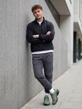 Tapered graphite nylon track pants worn with a black quarter-zip windbreaker and high-performance white crew socks for a sleek athletic aesthetic.