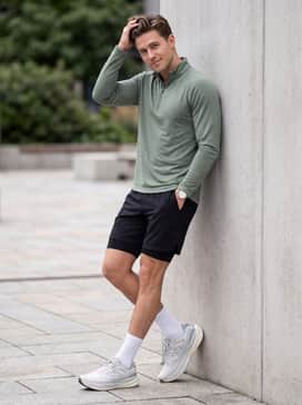 1080v15 Grey Days – Matte black athletic performance shorts worn with a sage green long-sleeve quarter-zip and high-performance white crew socks.