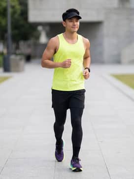 Black performance compression leggings paired with a neon yellow moisture-wicking singlet and a black running visor.