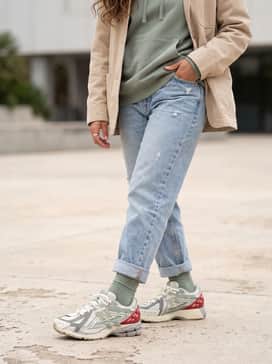 Light-wash distressed denim jeans worn with a sage green oversized hoodie and a beige chore coat to highlight the shoe's secondary color tones.