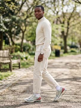 Ecru-colored chinos rolled at the ankle with a tucked-in cream mock-neck sweater and a minimalist silver-toned watch to complement the metallic detailing.