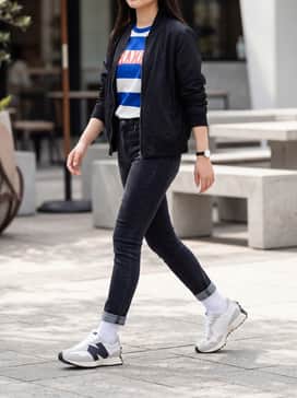 Dark-wash skinny jeans cuffed at the ankle, paired with a vibrant graphic t-shirt and a lightweight nylon bomber jacket.
