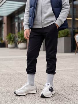 Tapered black joggers, a heather grey zip-up hoodie, and a bright puffer vest for a comfortable athletic look.