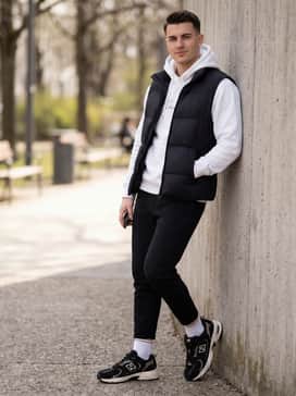 Tapered black joggers, a white graphic hoodie with gold lettering, and a sleek nylon puffer vest for a sporty, layered streetwear vibe.
