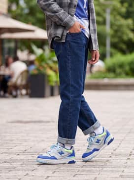 Cuffed straight-leg denim jeans with a graphic t-shirt featuring blue tones and an open flannel shirt for a layered, casual look.