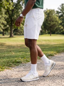 Summer Sport: Style with white athletic shorts, a forest green moisture-wicking performance tee, and a matching New Balance heritage baseball cap for a coordinated athletic aesthetic.