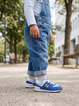 Classic denim overalls worn over a white long-sleeve striped shirt for a timeless and practical outfit.