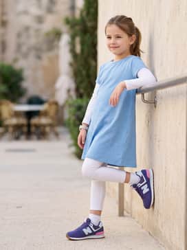 A playful weekend ensemble consisting of a light blue jersey cotton dress worn over white leggings for maximum comfort during active playdates.