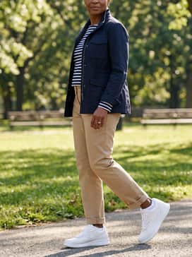 Tan chino trousers worn with a navy and white striped long-sleeve shirt and a utility jacket for a structured yet comfortable casual style.