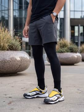 Acg Phassad – High-performance athletic gear including black compression tights, charcoal grey 5-inch running shorts, and a vibrant yellow moisture-wicking jersey to match the shoe's accents.