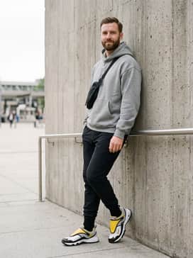 Acg Phassad – An urban utility ensemble consisting of tapered black tech joggers, a heavy-duty oversized hoodie in heather grey, and a black sling bag for a functional city vibe.