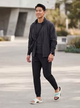 Match with tapered black track pants and a compression-fit long-sleeve top for a professional post-marathon recovery outfit.