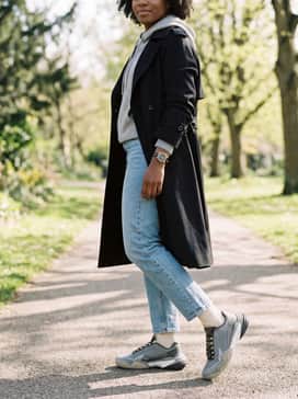 Casual Weekend Layering: Straight-leg light-wash denim cuffed at the ankle, a grey cashmere hoodie, and a structured black trench coat for a sophisticated yet sporty ensemble.