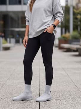 Black leggings with mesh panels, an oversized silver-grey hoodie, and a sleek ponytail for a high-performance athletic aesthetic.