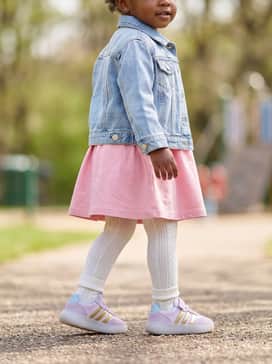 A birthday-ready style including a pink cotton A-line dress worn with white cable-knit tights and a light-wash denim jacket for a balanced aesthetic.