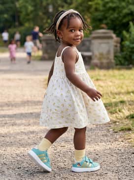 A simple white cotton sundress with small yellow floral prints to complement the gold accents on the shoes.