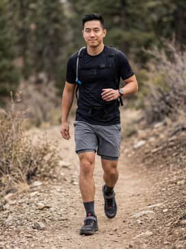 A black moisture-wicking short-sleeve jersey paired with grey technical mountain bike shorts and padded liner shorts for a functional trail-ready look.