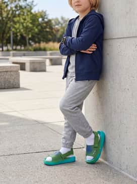Soft grey cotton joggers and a lightweight zip-up hoodie worn with white crew socks for a trendy, comfortable loungewear aesthetic.