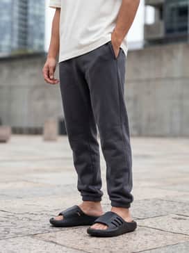 A relaxed streetwear outfit consisting of oversized grey sweatpants, a boxy white graphic tee, and chunky white crew socks to highlight the slide's bold silhouette.