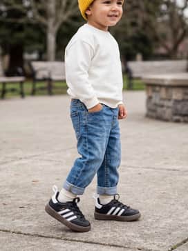 A casual weekend outfit with light-wash cuffed denim jeans, a soft white crewneck sweater, and a bright yellow beanie.