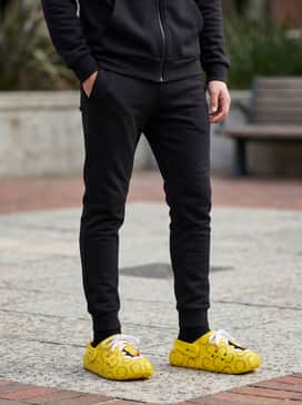 Adilette Clog  Simpson – A monochromatic black tracksuit comprising slim-fit joggers and a zip-up hoodie to make the yellow clogs the focal point.