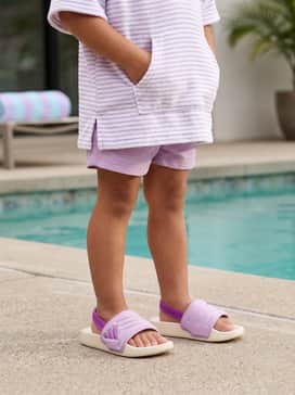 Adilette Estrap 20 Slides Children – A lavender-toned one-piece swimsuit or patterned swim trunks layered under a white terry cloth hooded cover-up for a functional poolside outfit.