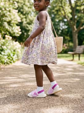 Adilette Estrap 20 Slides Children – A floral print cotton sundress featuring soft lilac and cream tones, paired with a small straw bag for a charming and breezy picnic-ready ensemble.