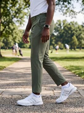 Tapered olive green golf trousers combined with a crisp white tech-fabric polo and a sleek silver smartwatch.