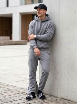 Grey tech-fleece joggers combined with a matching oversized hoodie and a black baseball cap for a cozy and cohesive athleisure vibe.