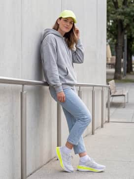 Adistar 4 Running Shoes – Casual streetwear style including light-wash cropped slim jeans, a neutral grey oversized hoodie, and a neon yellow baseball cap to coordinate with the footwear.