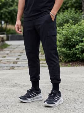 Tapered black cargo pants with utility pockets, an oversized silver-grey hoodie, and a minimalist black backpack for a futuristic tech-inspired street style.