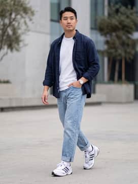 Light-wash tapered denim jeans paired with a crisp white heavyweight t-shirt and a navy blue unbuttoned flannel shirt for a classic casual vibe.