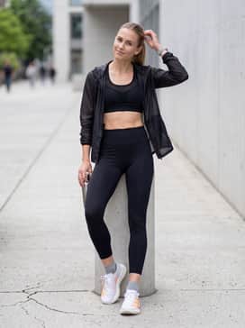 A sleek monochromatic black athletic set with a mesh-panelled sports bra and a lightweight, translucent running jacket that echoes the shoe's airy feel.