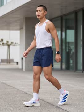 A professional race-day look featuring lightweight, split-leg running shorts in navy and a breathable mesh white singlet with red accents.