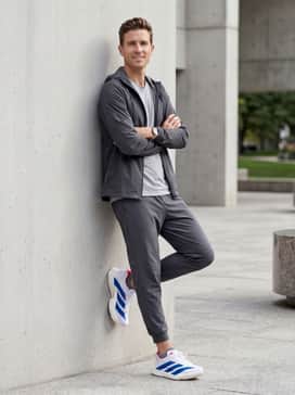 A modern warm-up outfit with tapered charcoal gray athletic joggers, a matching technical windbreaker, and performance-grade no-show socks.