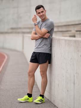 A high-intensity training outfit with a grey heathered performance tee, split running shorts in a neutral tone, and technical low-cut socks.