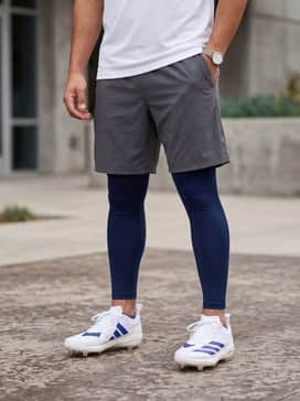 Adizero Electric 20 Baseball Cleats – Navy blue compression leggings worn under charcoal grey mesh training shorts, paired with a fitted white moisture-wicking performance t-shirt for practice sessions.