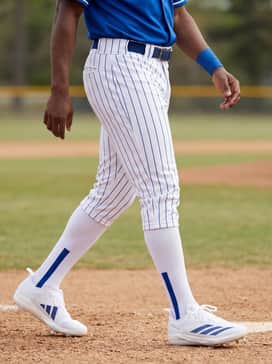 Adizero Electric 20 Baseball Cleats – Classic white baseball trousers with a blue pinstripe, paired with a professional team jersey and blue wristbands for a clean, professional diamond aesthetic.