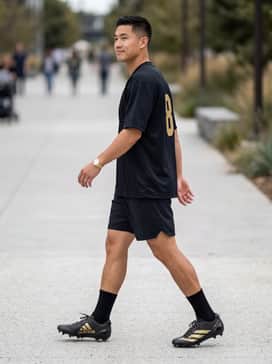 A matching black team jersey with gold numbering paired with padded football pants and moisture-wicking crew socks for a cohesive game-day look.
