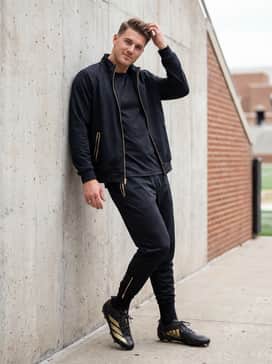 A full tapered black tracksuit with subtle gold accents on the zippers to mirror the cleats color scheme for pre-game arrivals or post-game travel.