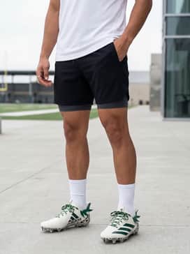Adizero Electric Ii Polynesian Bowl Football Cleats – Training session ensemble: Style with moisture-wicking black athletic shorts and a white performance tech tee, allowing the intricate green patterns and heel detail of the cleats to stand out.