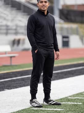 Tapered black technical joggers combined with a moisture-wicking quarter-zip training pullover and a breathable athletic headband for off-season drills.