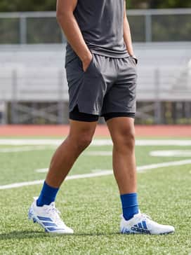 Adizero Electric Ii Smu American Football Cleats – Black performance compression leggings worn under charcoal grey athletic shorts with a moisture-wicking white technical tee for training drills.