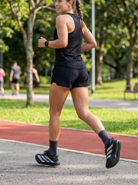 A summer training kit including 5-inch split running shorts in matte black, a white mesh tank top, and high-performance charcoal crew socks to bridge the shoe and leg.