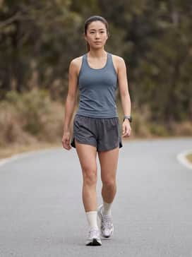 A performance-driven outfit featuring charcoal grey 2-in-1 running shorts, a slate-colored racerback tank, and a lightweight GPS watch for a focused marathon training session.