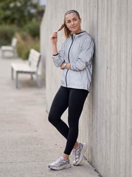 A functional outdoor ensemble with black thermal running tights, a reflective silver windbreaker jacket, and a moisture-wicking headband for early morning jogs.