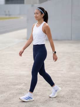 High-waisted navy compression leggings paired with a white moisture-wicking racerback tank and a light blue performance headband for a coordinated track look.