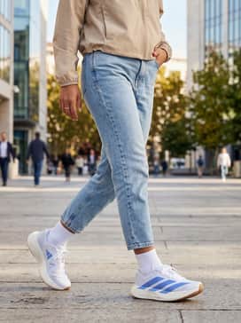 Adizero Evo Sl Shoes – Light-wash cropped tapered jeans worn with a boxy white graphic t-shirt and a beige windbreaker for a fresh, sporty-casual weekend ensemble.