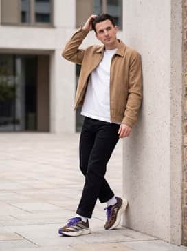 A clean weekend look consisting of straight-leg black jeans, a fitted white crewneck tee, and a neutral tan harrington jacket that grounds the bold animal print.