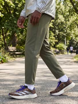 A performance-ready ensemble with white crew socks, olive green technical joggers, and a metallic silver windbreaker that echoes the iconic three-stripes.